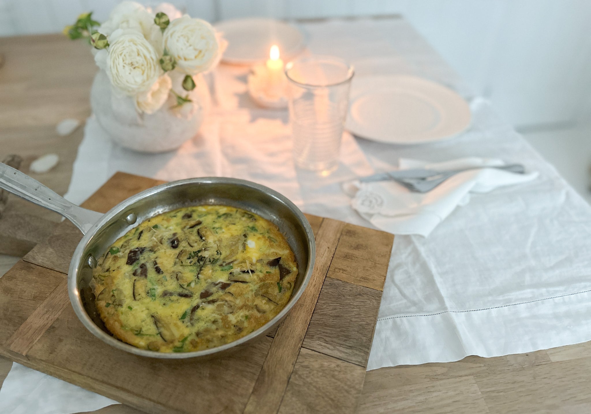 romantic table setting with a handmade frittata in pan fresh from the oven