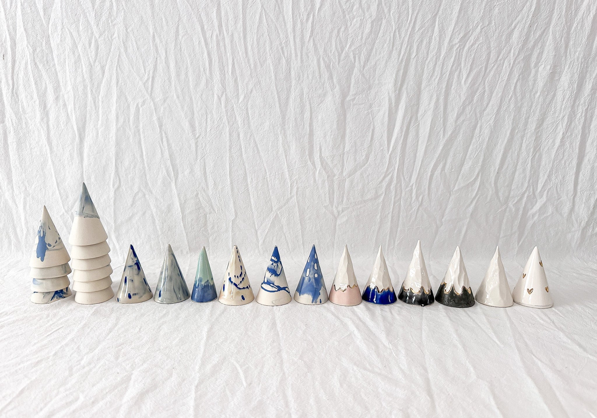 Row of one-of-a-kind handmade ceramic ring cones in varied neutral and blue glaze tests.