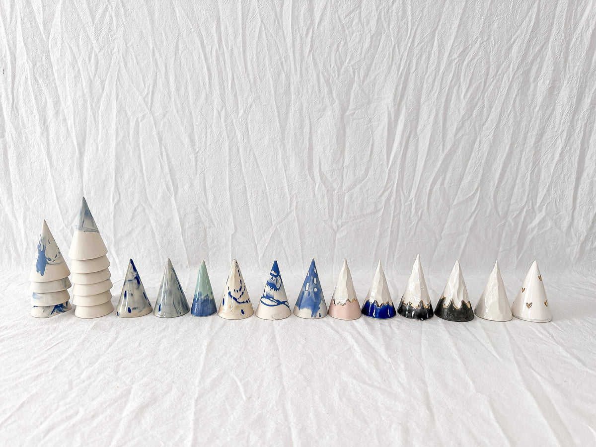 Row of one-of-a-kind handmade ceramic ring cones in varied neutral and blue glaze tests.