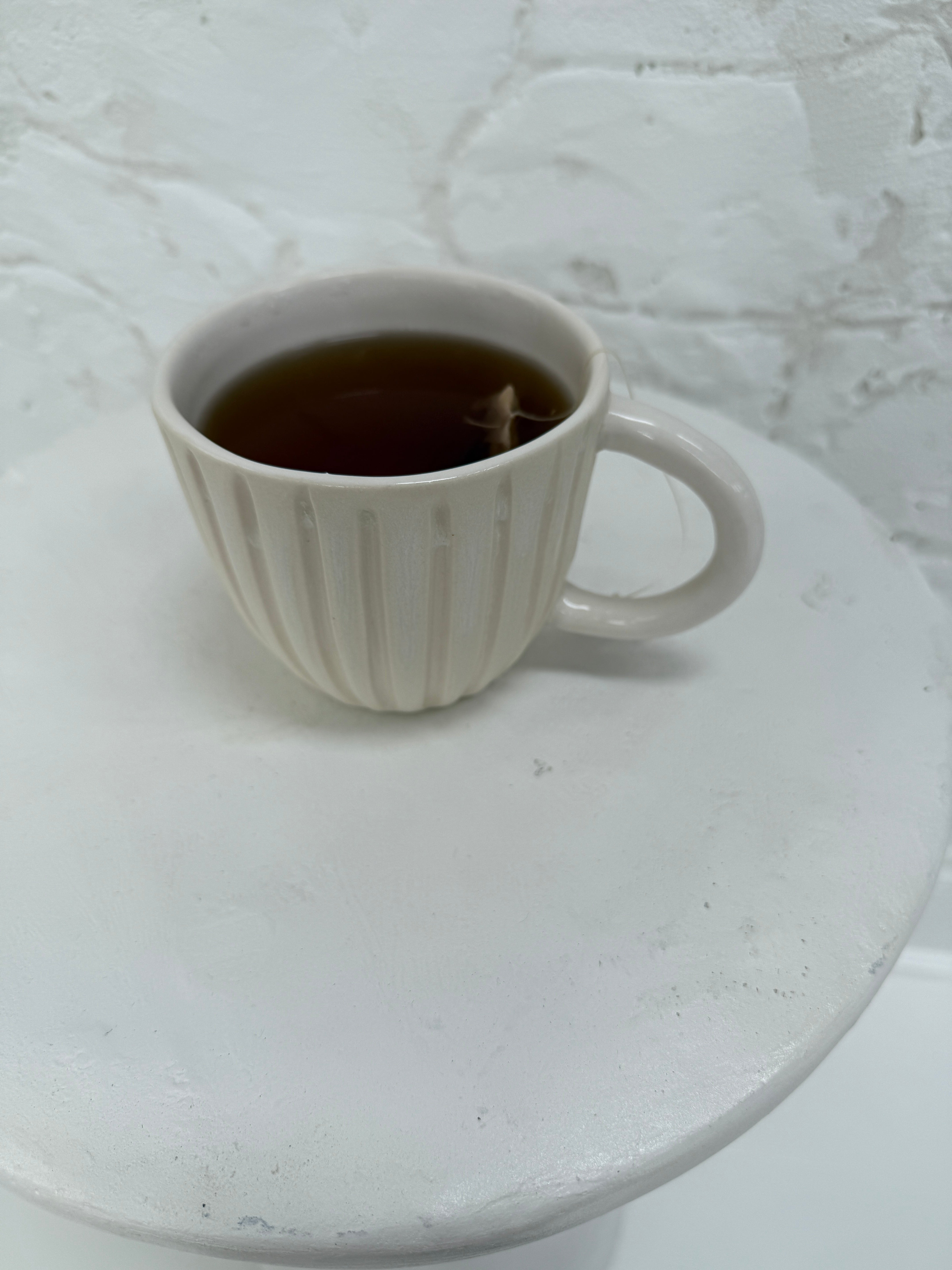 Handmade fluted ceramic cup filled with tea, a slow morning ritual