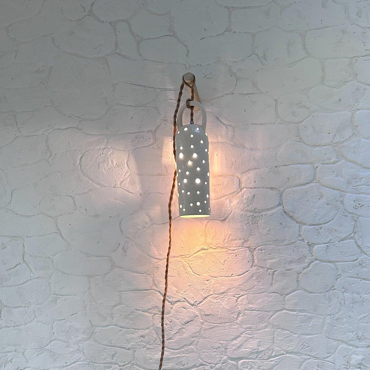 Handmade stoneware lamp with hand-carved star cutouts casting a starry glow